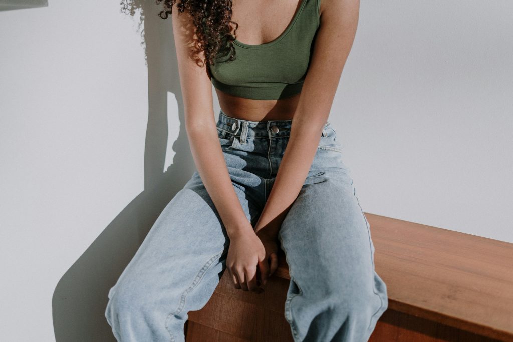 Woman in Black Tank Top and Blue Denim Jeans Sitting on Brown Wooden Bench