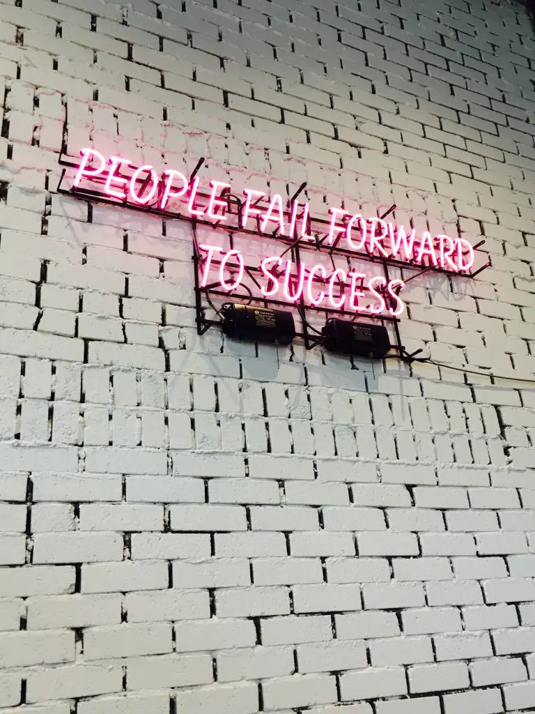 neon sign in pink saying people fail forward to success