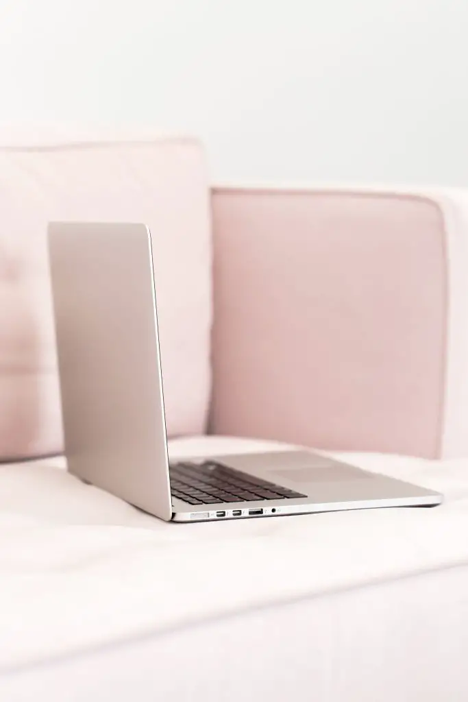 pink laptop sitting on pink sofa