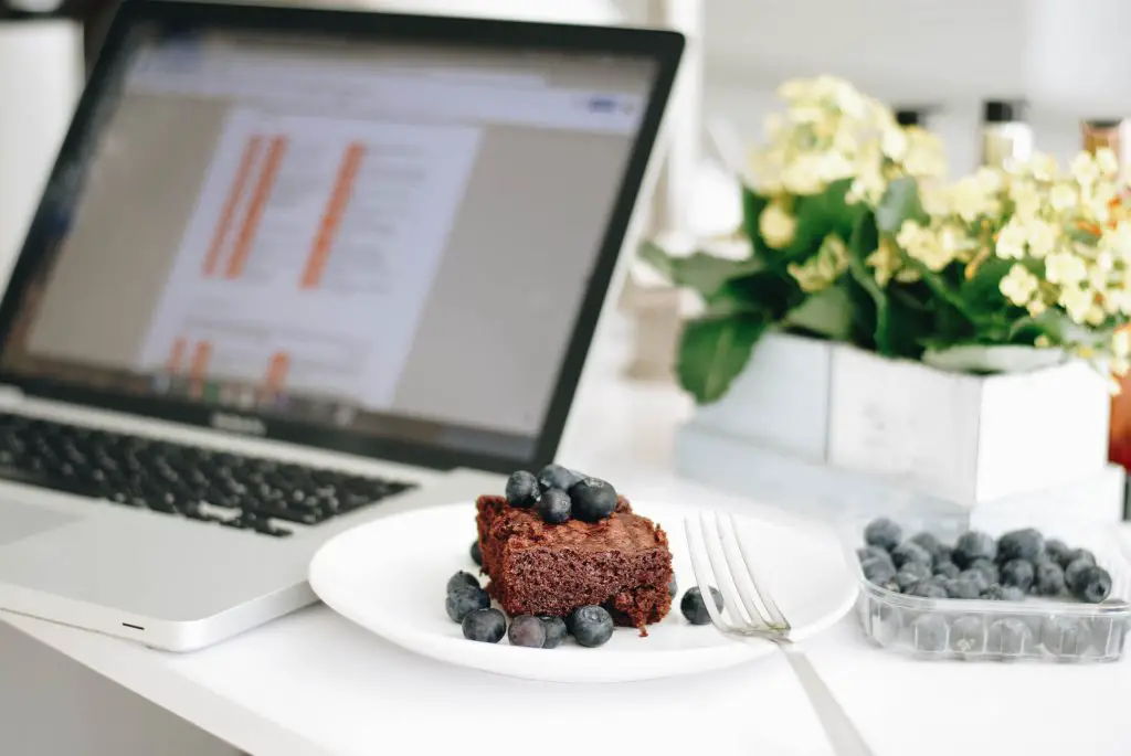 chocolate cake with blueberries beside macbook