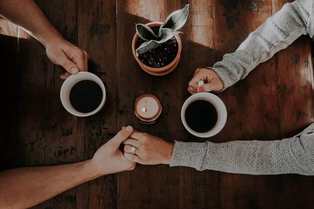 people holding hands and holding coffee mugs