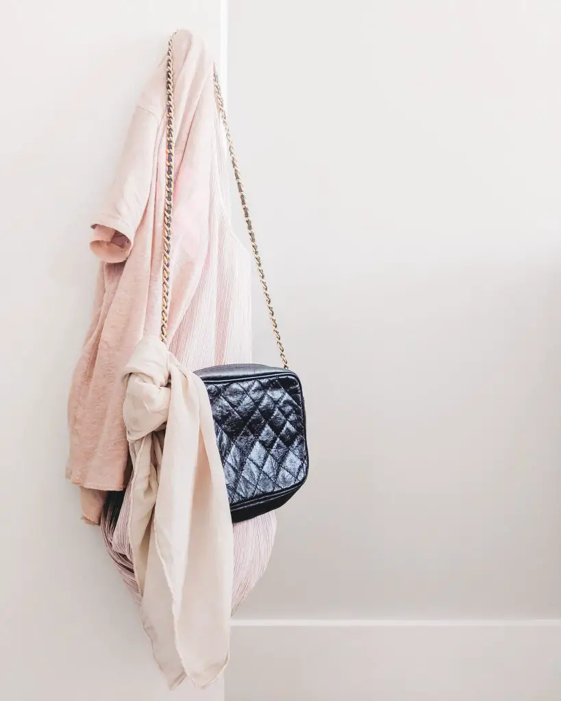 pink t-shirt hanging with black handbag on hook