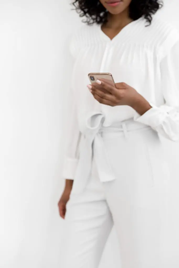 woman standing wearing all white holding phone