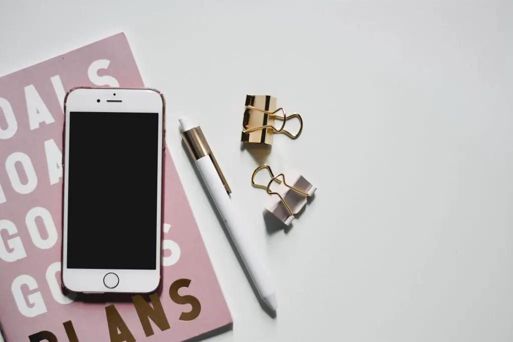 i phone 6 on pink and gold card beside gold and white pen 