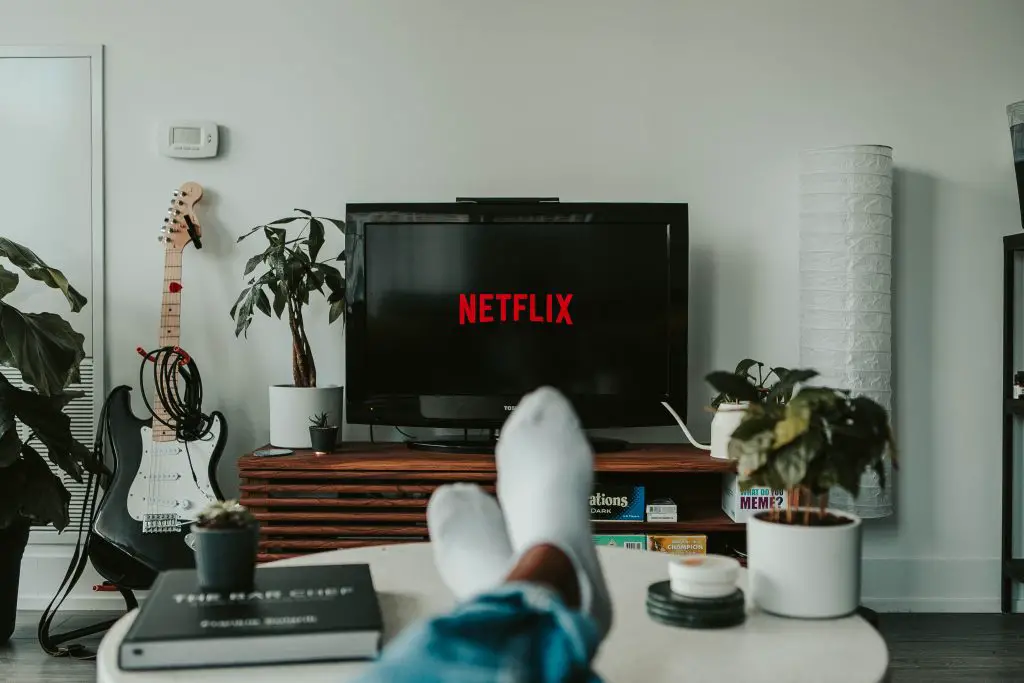 persons feet on table watching Netflix on flat screen TV
