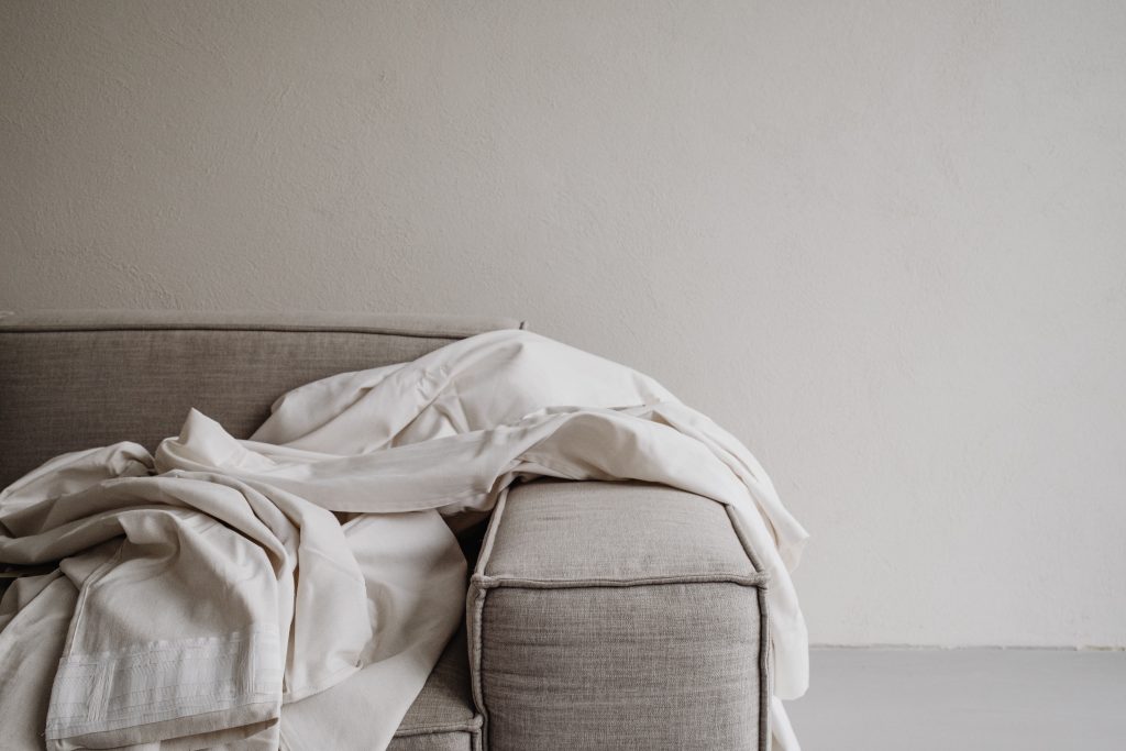 white sheets draped over corner of grey sofa