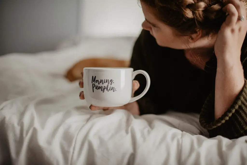 woman drinking coffee in bed -How to Make Mornings Easier When You Have Chronic Pain