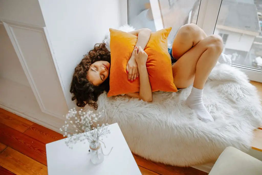 woman hugging orange pillow