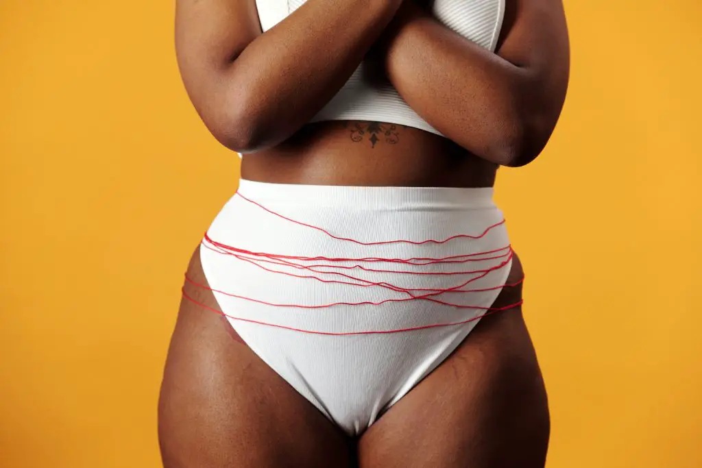 woman in underwear with red thread wrapped around pelvic area