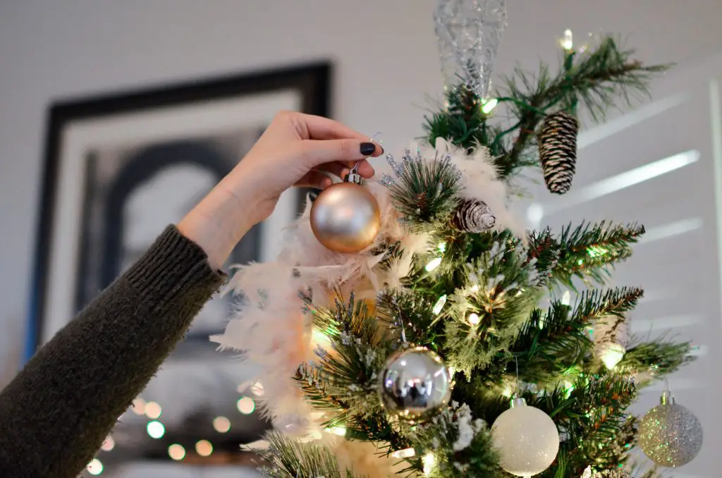 person putting bauble on Christmas tree