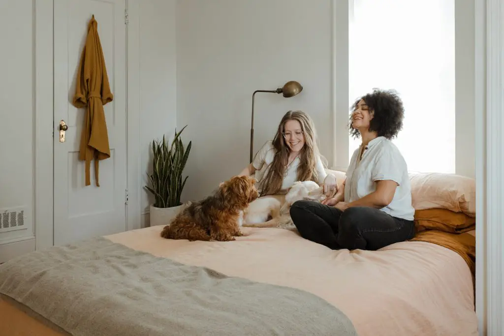 two women and dog sitting on bed