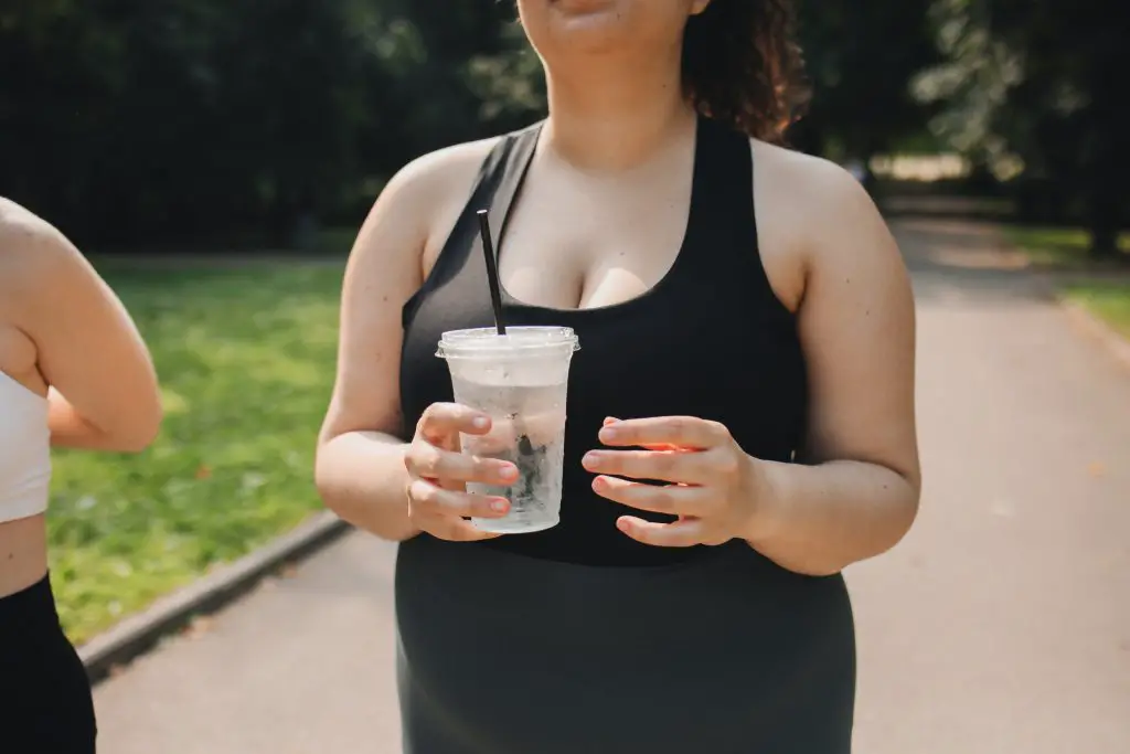 woman in park holding tumbler of water 