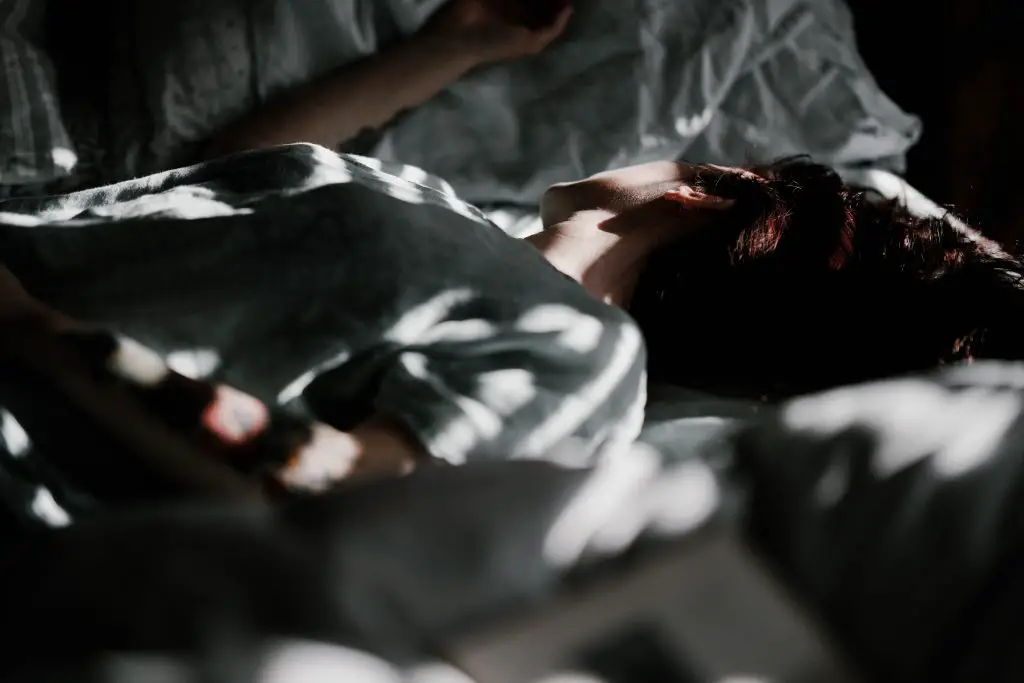 woman lying on bed in dark room