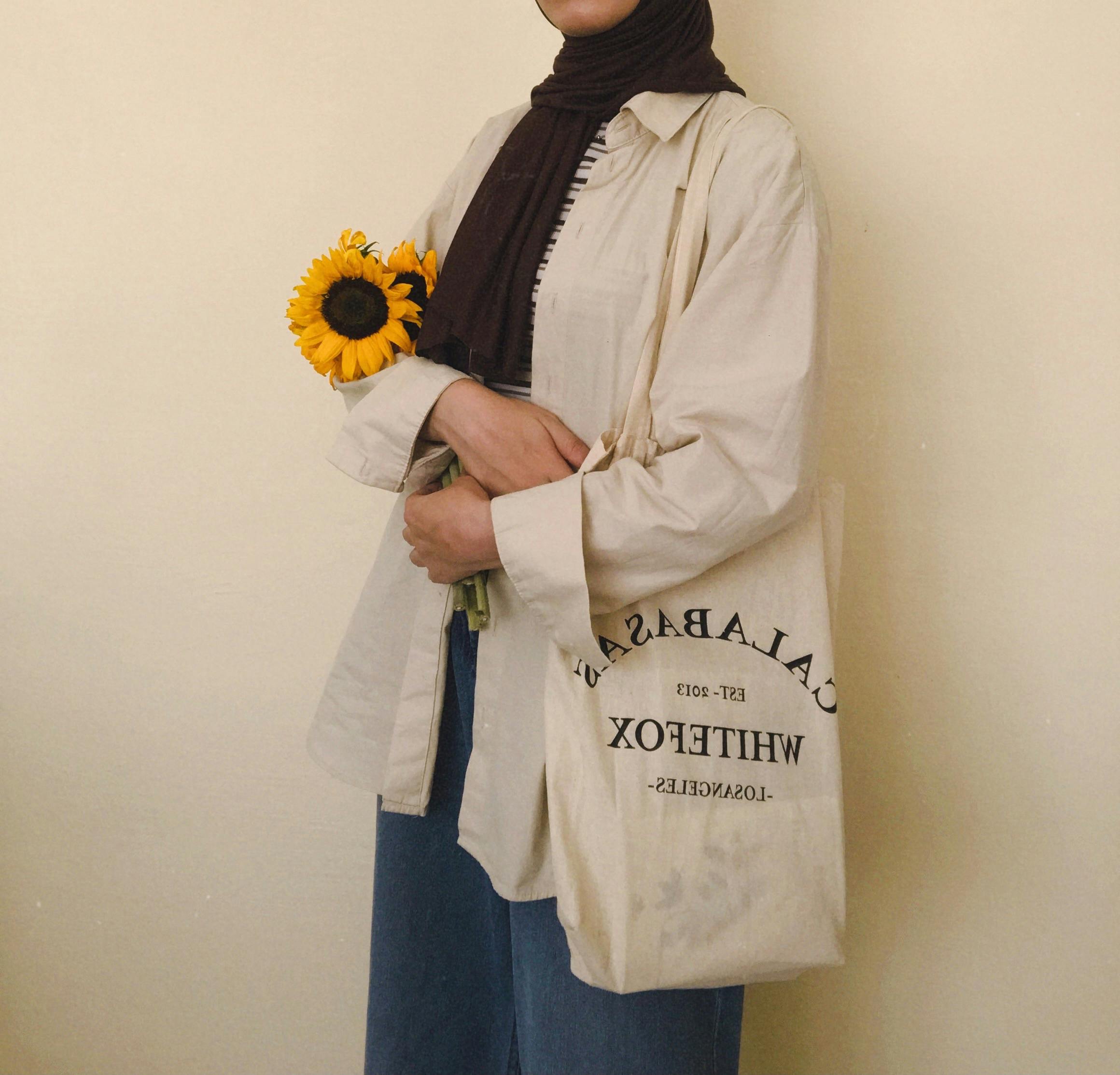 woman with vintage tote bag on shoulder holding a sunflower