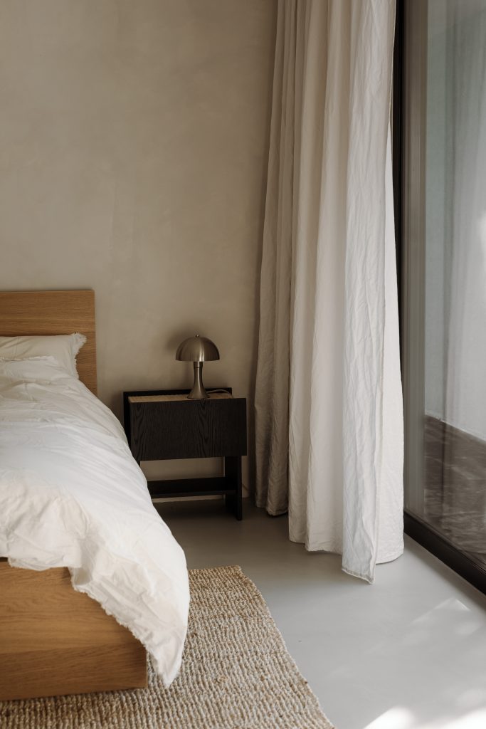 bed beside neutral curtains
