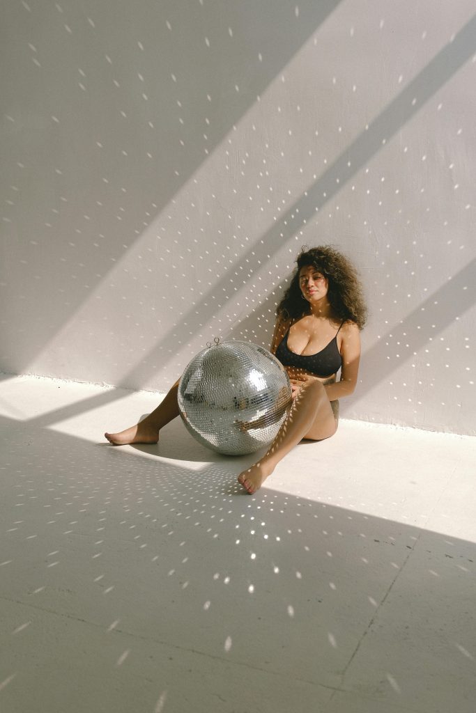 woman sitting on floor holding large glitter ball