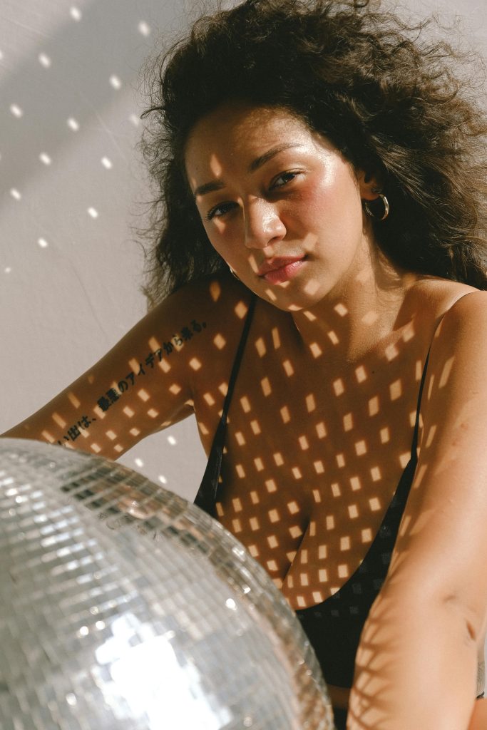 woman in black bikini holding large glitter ball