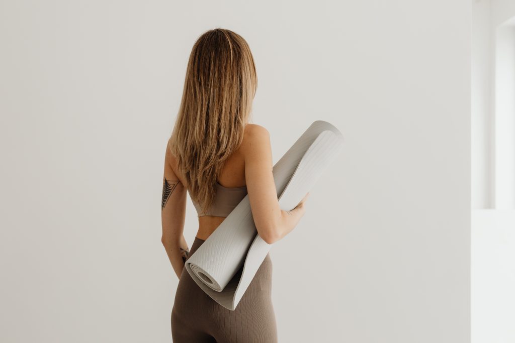behind woman holding yoga mat