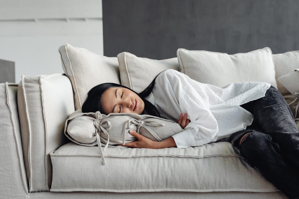 young asian woman lying down on couch