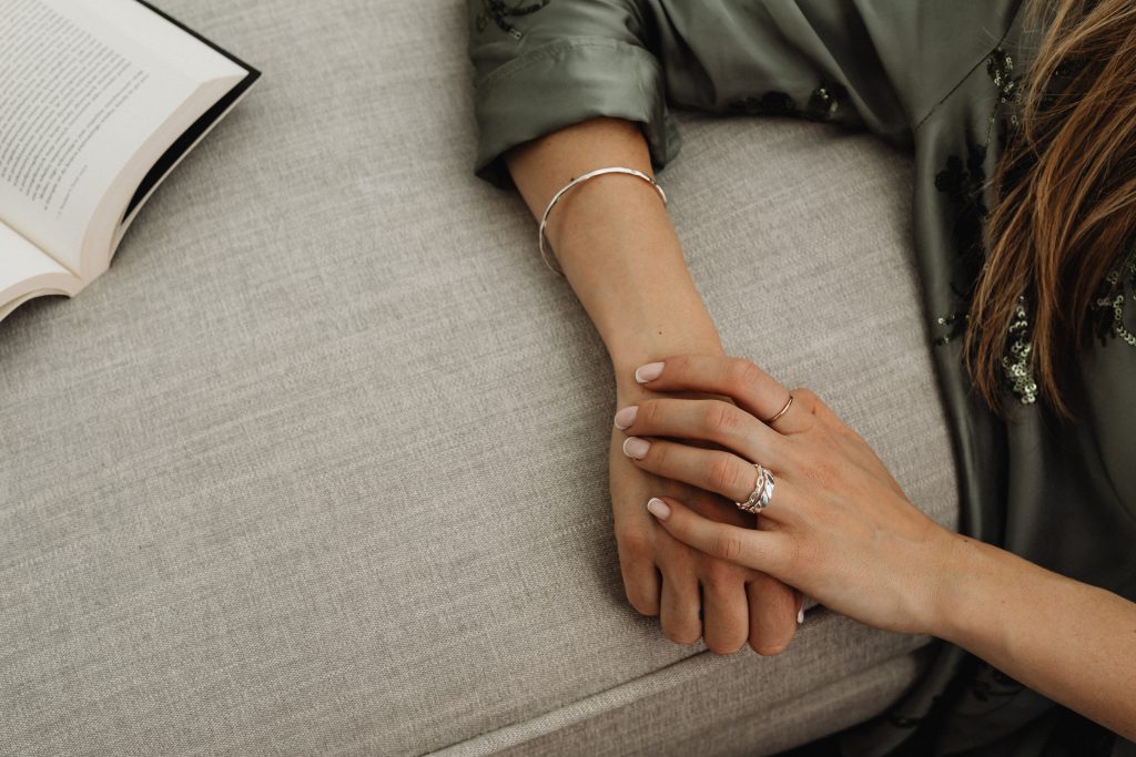 womans hand with silver rings leaning on sofa