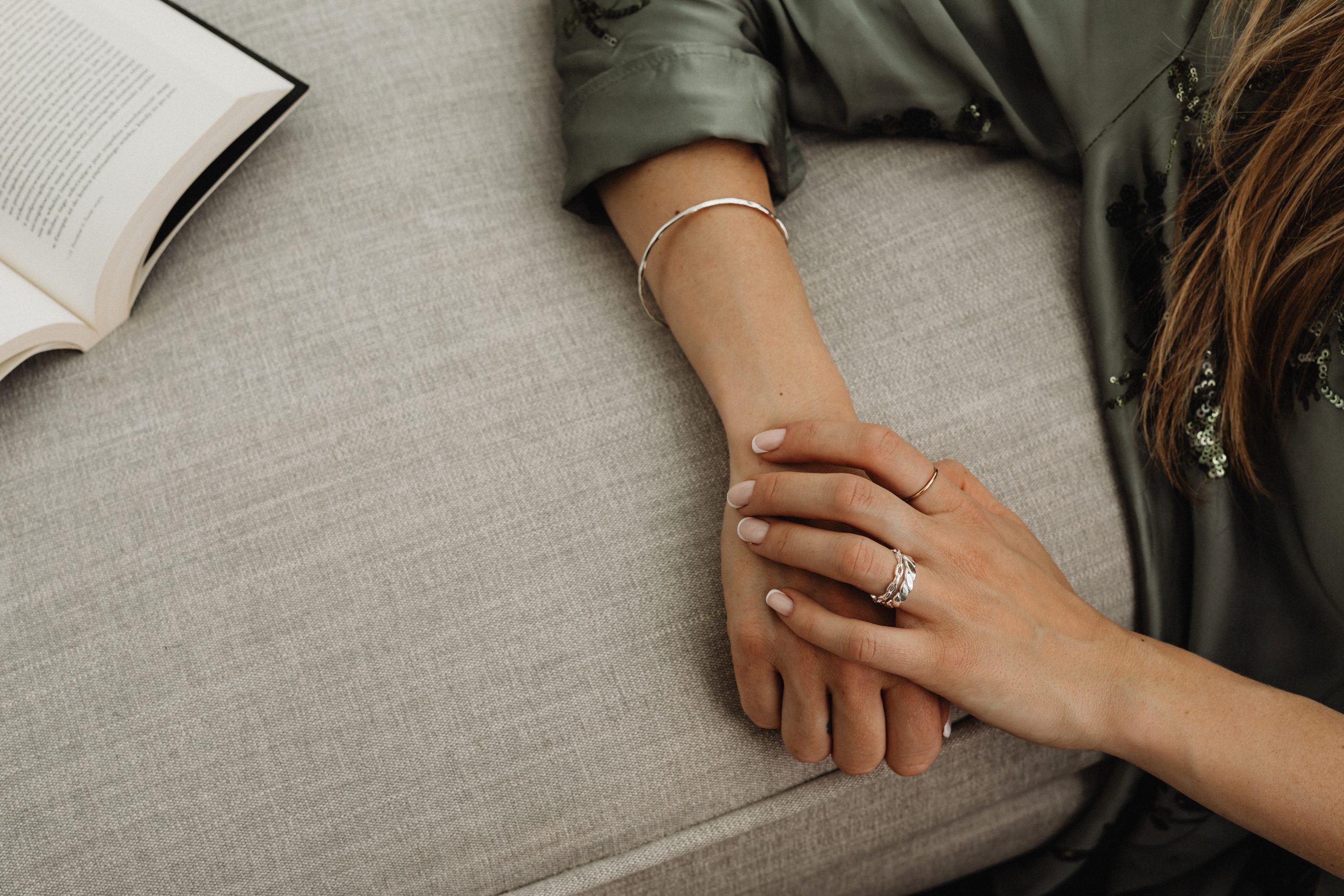 womans hand with silver rings leaning on sofa