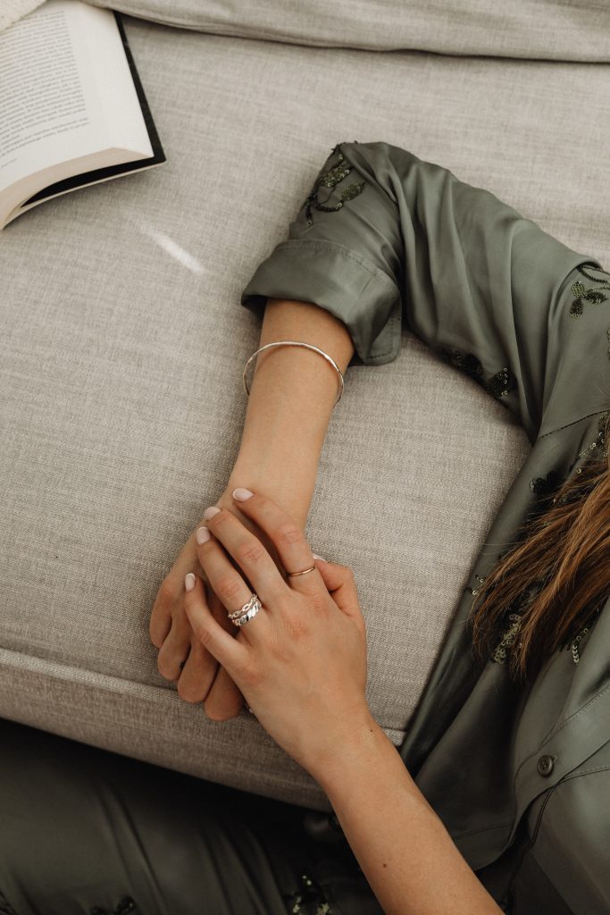 womans hand with silver rings leaning on sofa