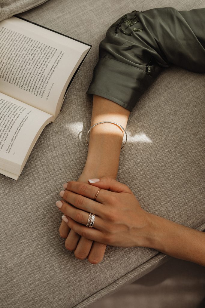 womans hand with silver rings leaning on sofa