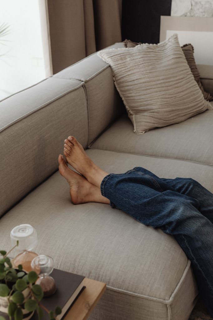woman with legs up on grey sofa