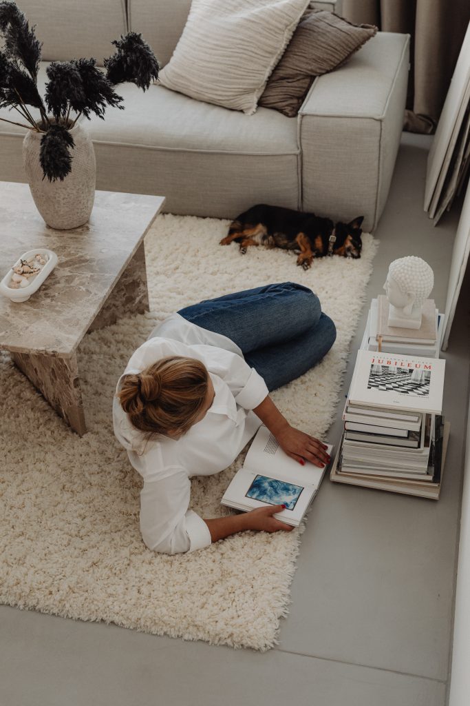 woman lying on rug on floor reading