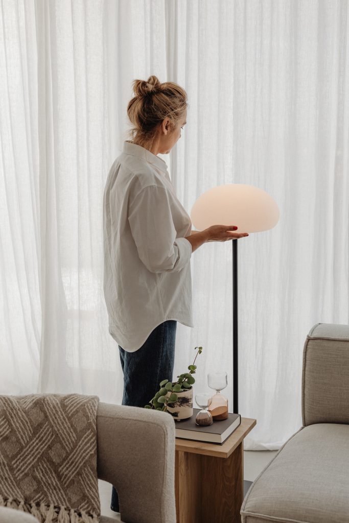 woman turning on lamp in front of window