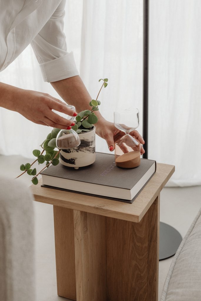 woman placing plant on wooden coffee table