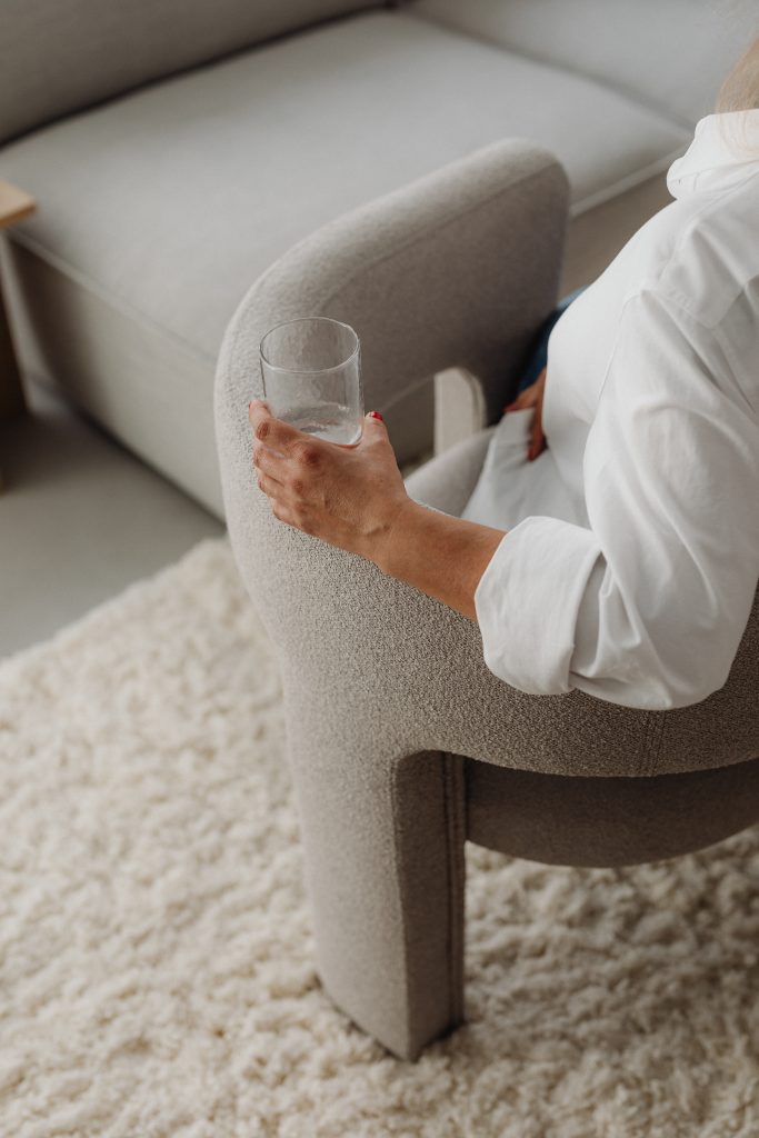 woman sitting on grey chair holding glass