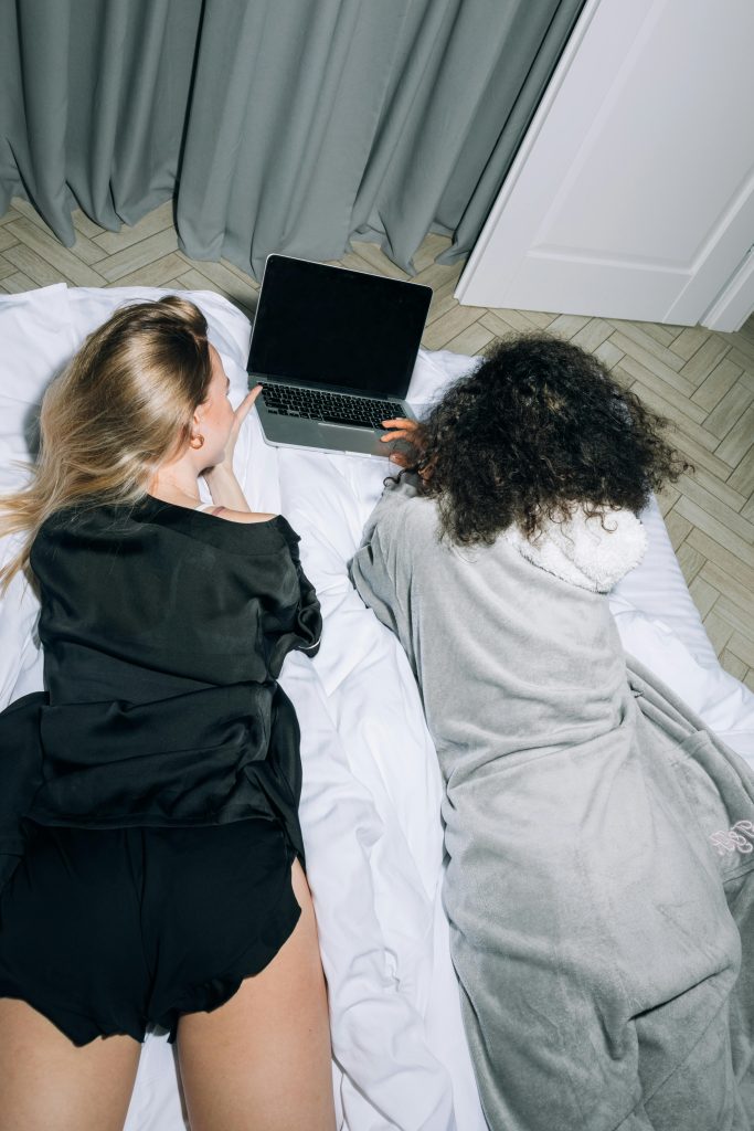 woman lying on bed looking at laptop screen