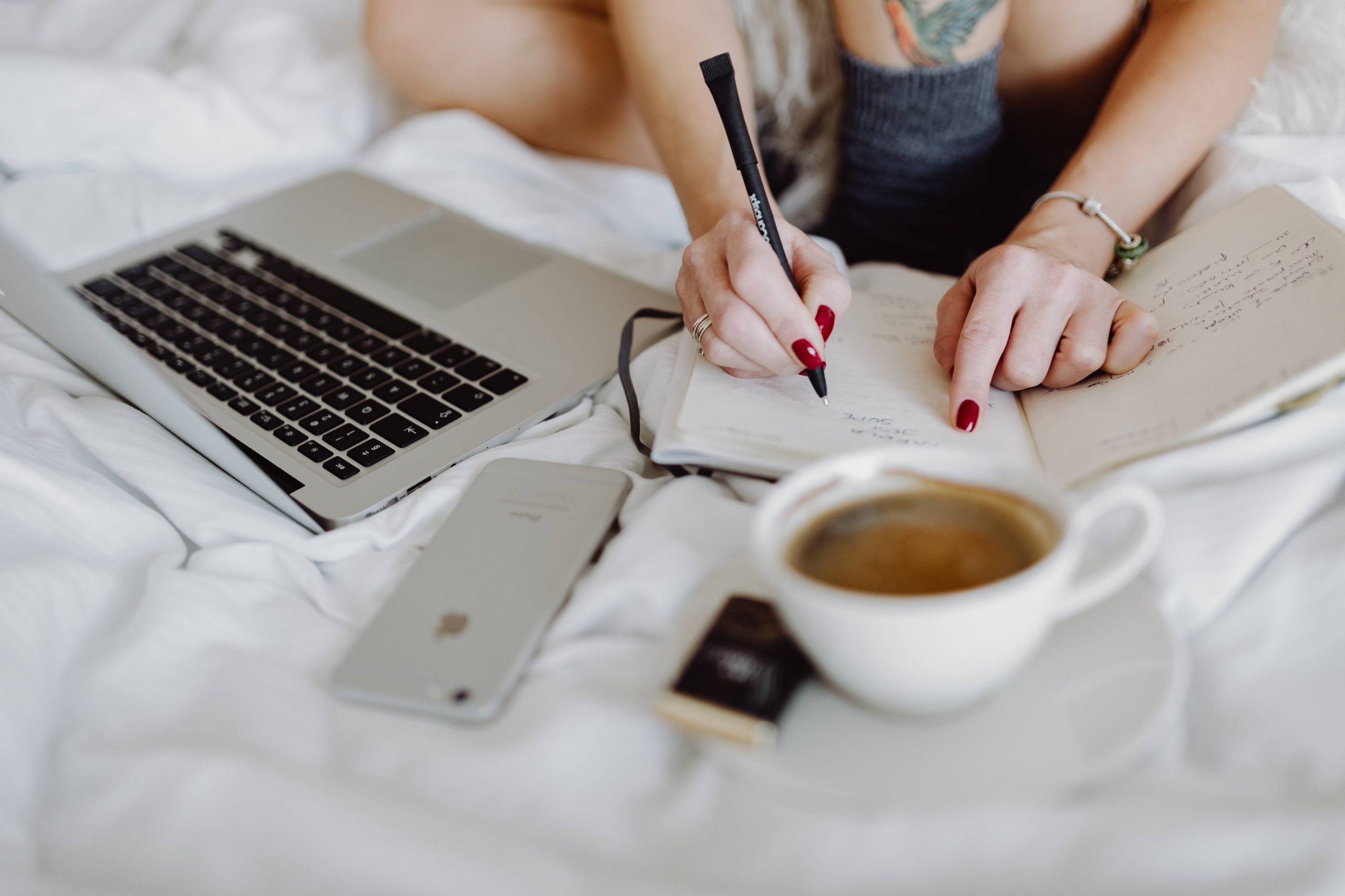 woman sitting on bed wriritn in notebook