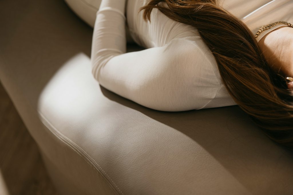WOMAN HOLDING PELVIS LYING ON COUCH