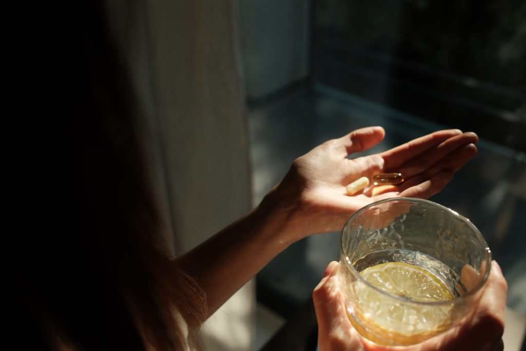 Woman holding vitamins and ghass of water