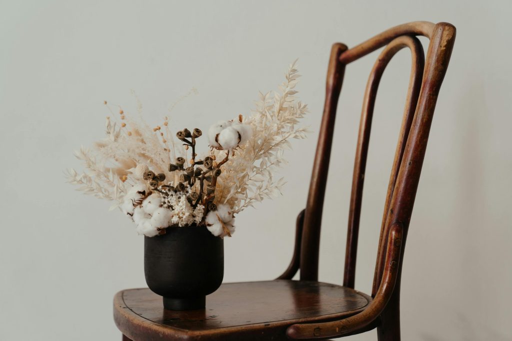 Dried flowers in black vase on woode chair