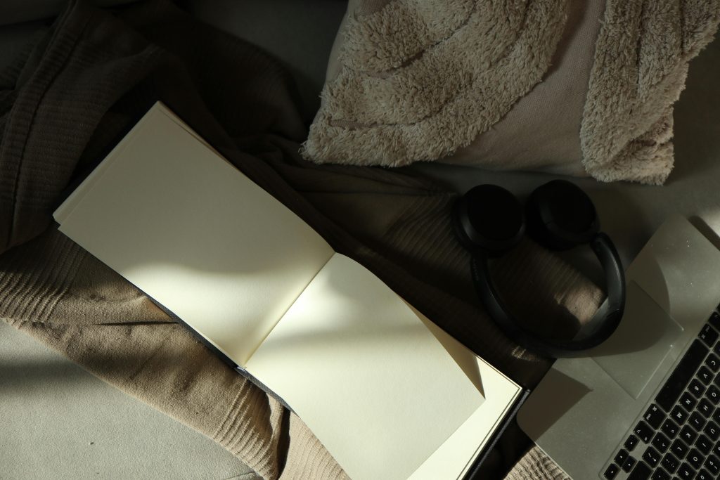 notebook on grey sheets beside pillow