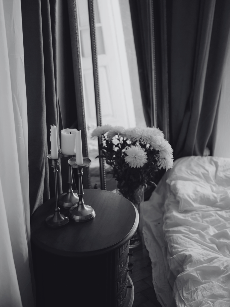 flowers and candles on table beside bed