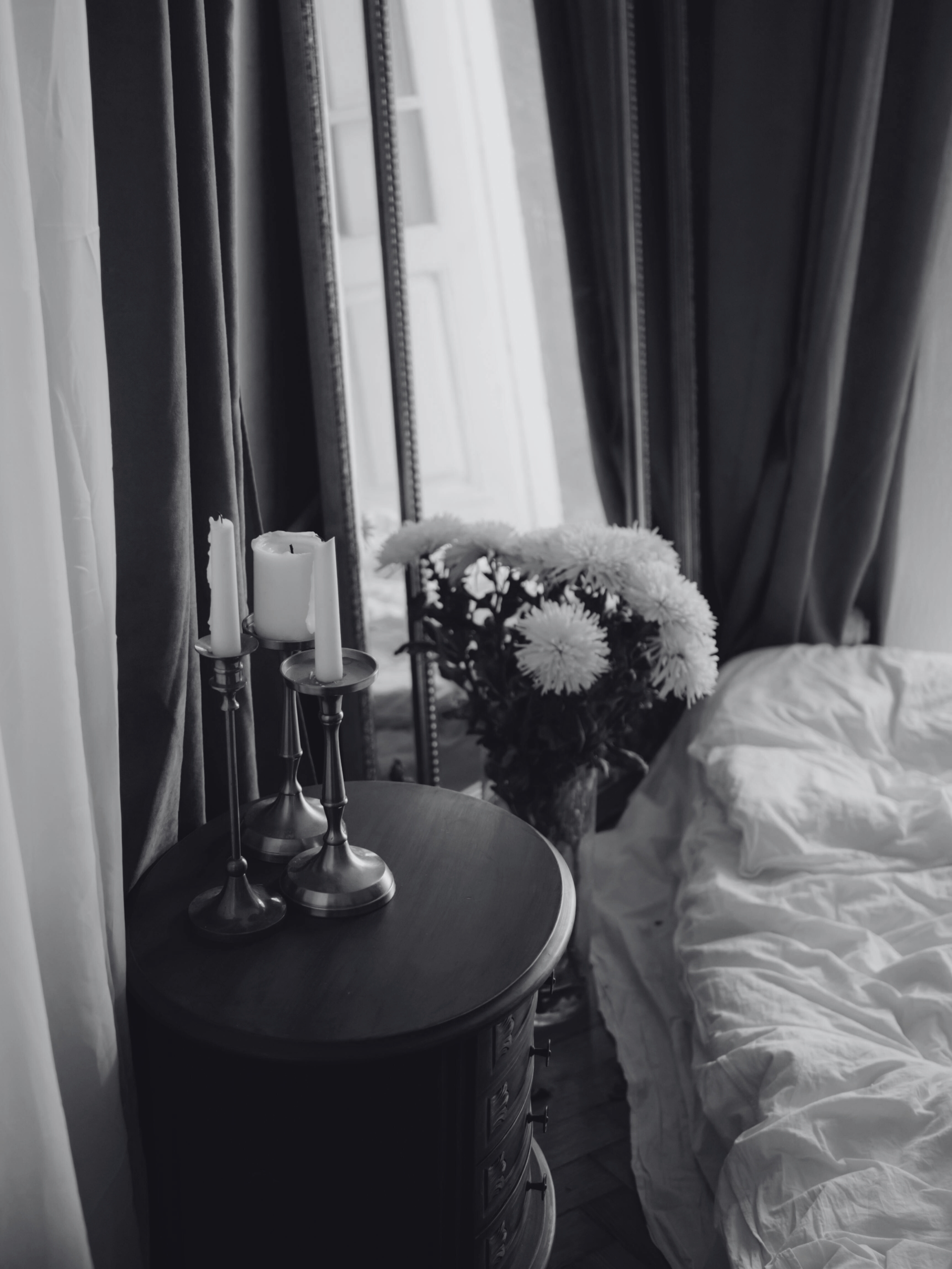 flowers and candles on table beside bed