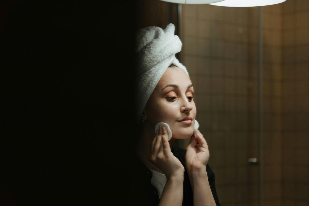woman in mirror doing skincare