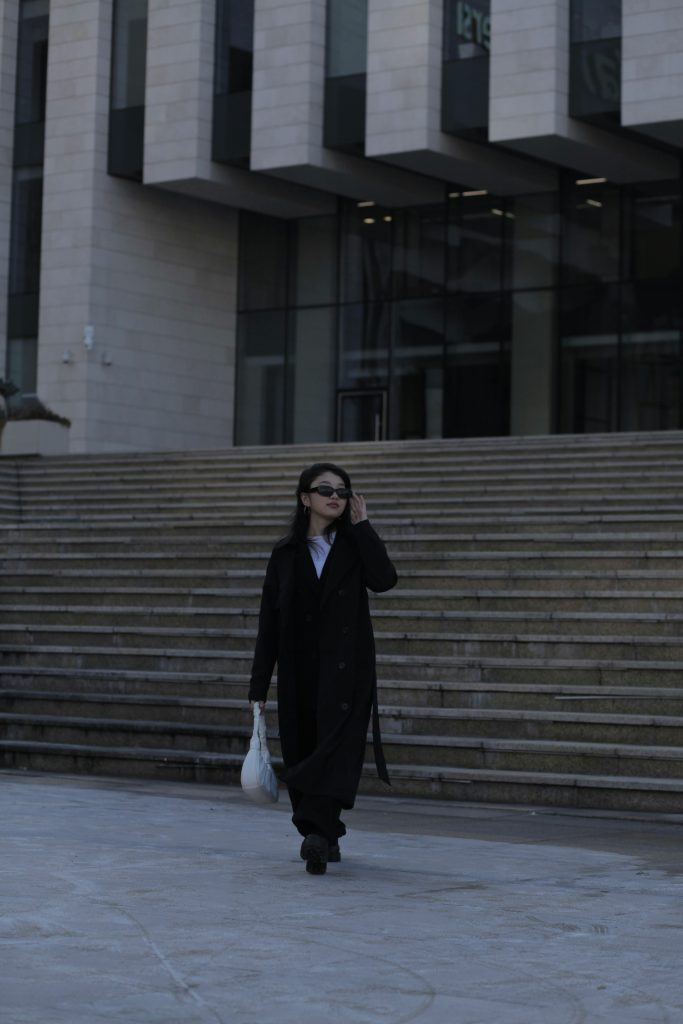 woman in black coat with white handbag walking