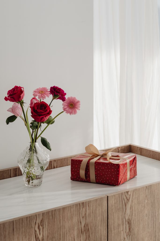 Vase of flowers beside red wrapped gift