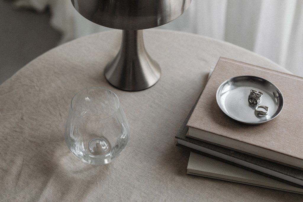 metal lamp on brown table beside eater and pile of books