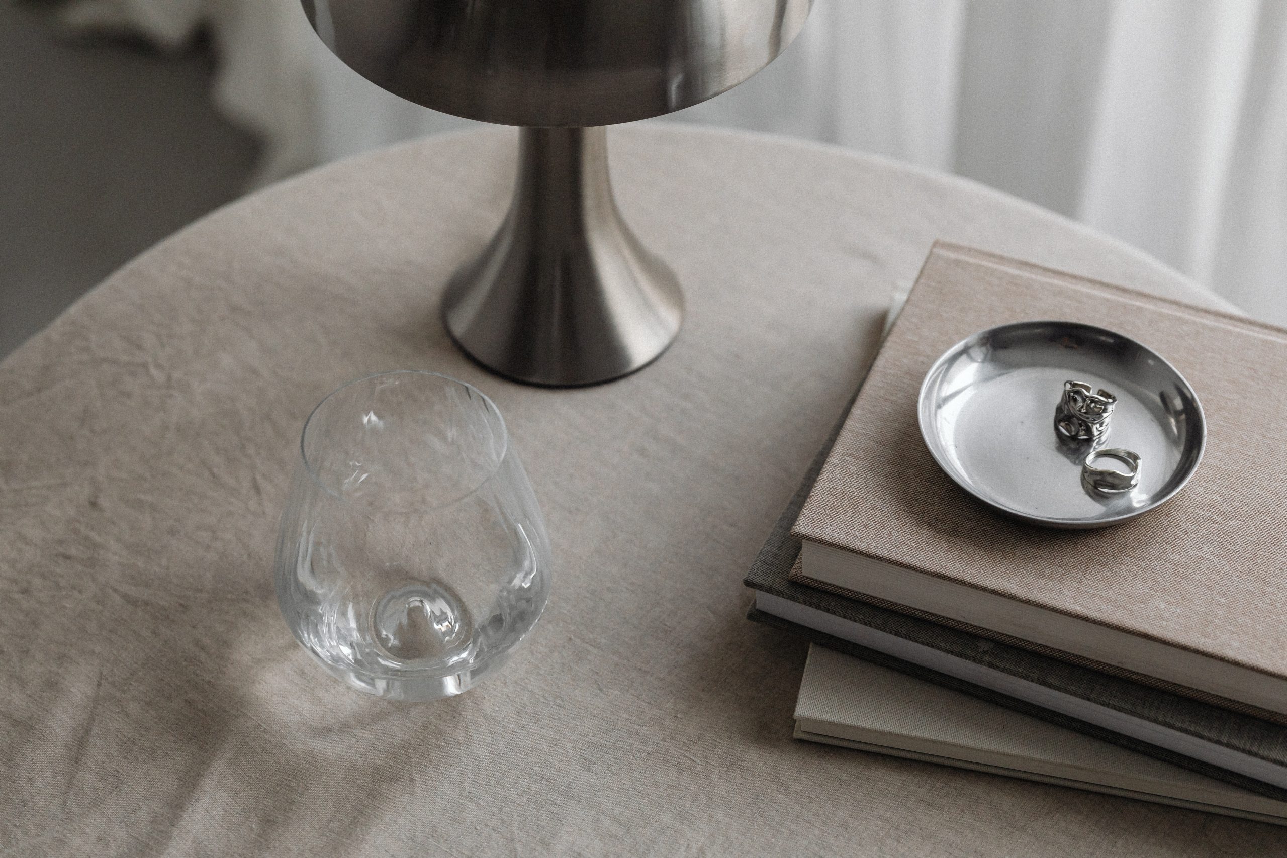 metal lamp on brown table beside eater and pile of books