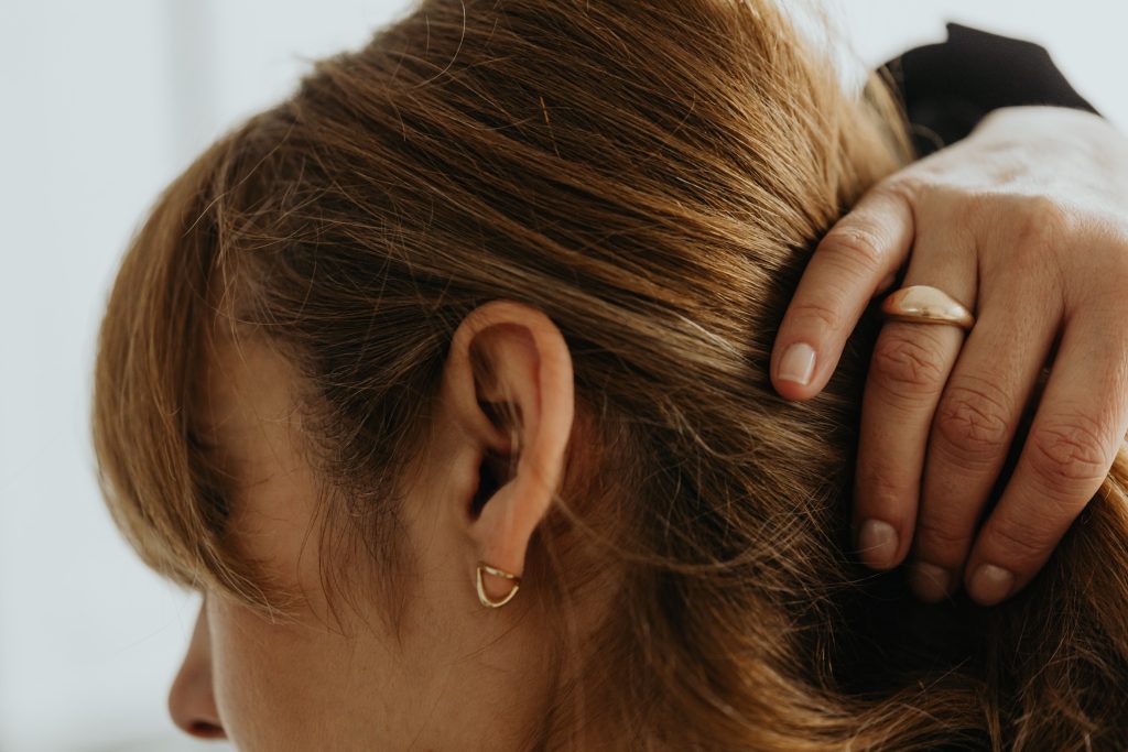 back of womans head with her hand with gold rings