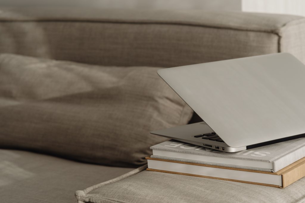 laptopn on pile of books half closed on corner of sofa