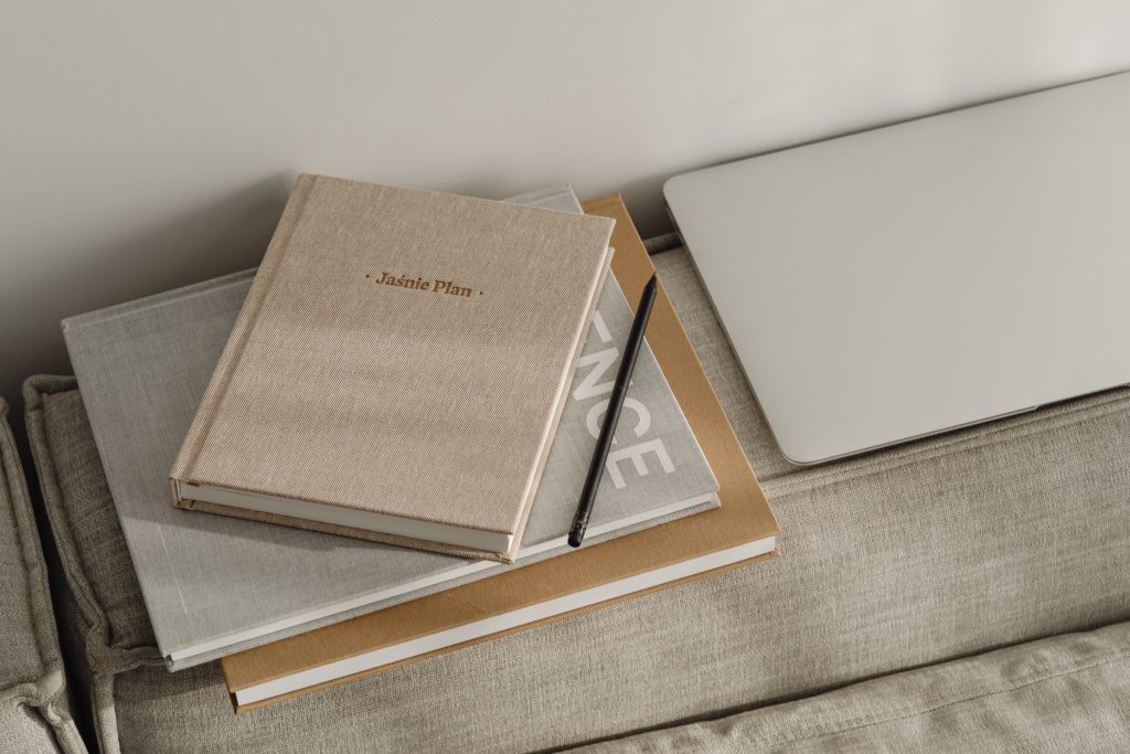 piles of books an closed laptopn on sofa