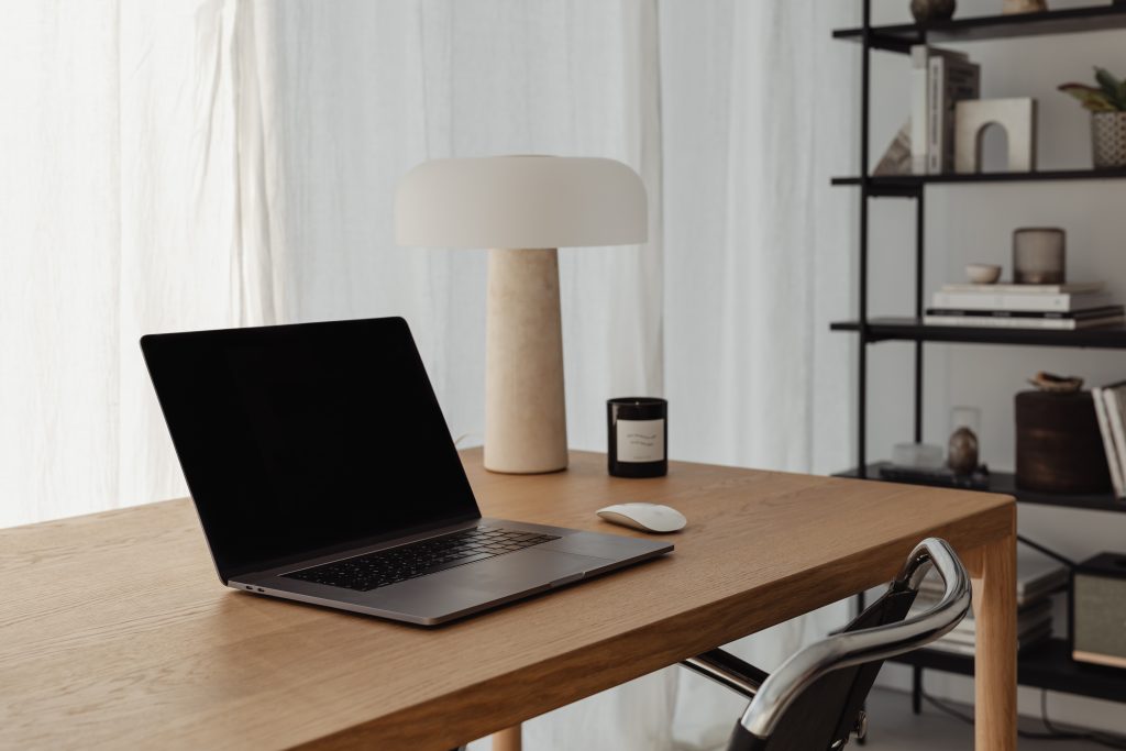 laptopn on desk beside wodden lamp
