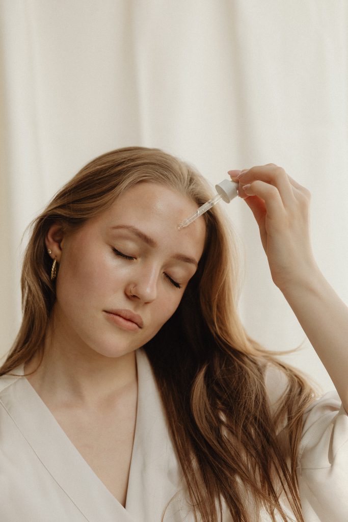 woman puttin on oil on face